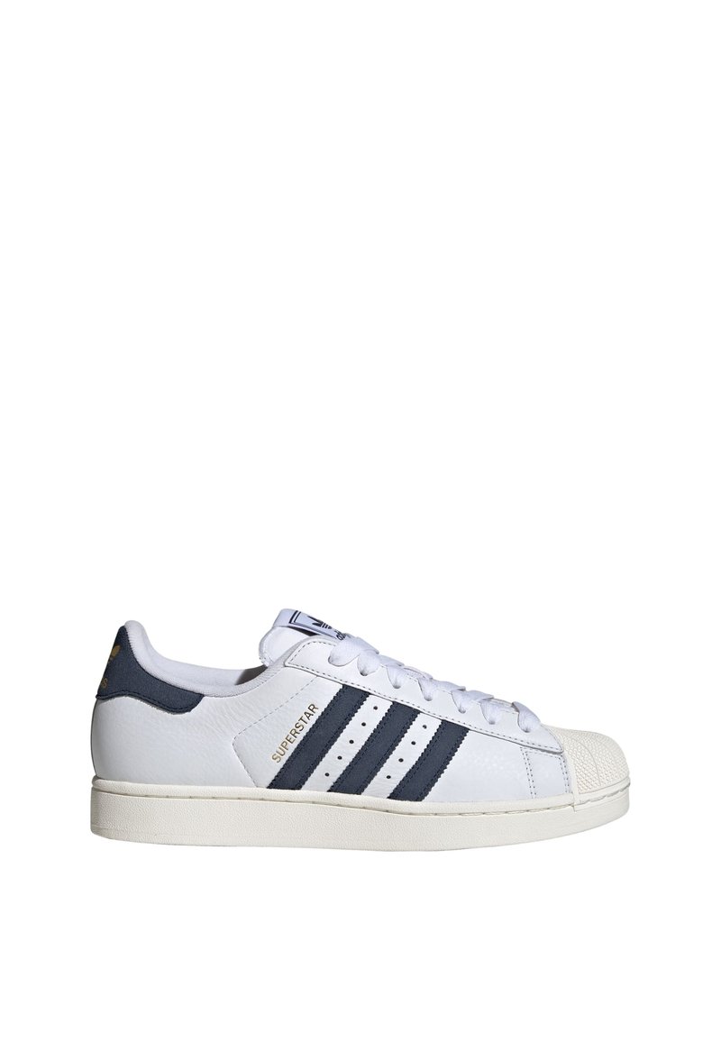White leather sneaker with black stripes, "SUPERSTAR" label, rubber shell toe, and white laces on a flat off-white sole.