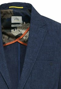 Blazer bleu marine texturé avec doublure intérieure à motif floral, passepoil orange et étiquette logo Camel Active à l'intérieur du col.
