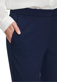 Námořnické kalhoty vyrobené z hladké tkaniny s přiléhavým střihem, se bočními kapsami a čistým designem pasu.