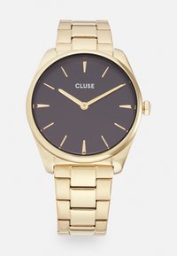Gold metal wristwatch with a black dial, featuring gold hour markers and hands. The bracelet has a linked design with a polished finish.