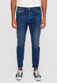 Blue denim jeans with a slim fit, featuring classic five-pocket design, light fading, and stitched detailing at the waist and hem.