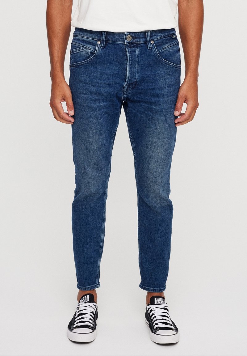 Blue denim jeans with a slim fit, featuring classic five-pocket design, light fading, and stitched detailing at the waist and hem.