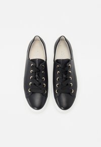 Sorte lær sneakers med flade sorte snørebånd, gyldne øjer, en afrundet tå og en hvid gummisål. Glat overflade med minimal detaljering.