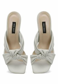 Light gray leather heeled mules with a knotted design at the toe, square toe shape, and a smooth inner lining. Brand tag visible.