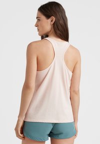 Ljusrosa ärmlös linne med racerback-design. Mjuk tyg och avslappnad passform, parat med teal träningsshorts.