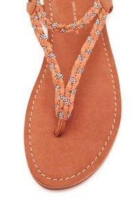 Chanclas de cuero color bronce con tiras trenzadas adornadas con tachuelas plateadas, que cuentan con una plantilla acolchada y un detalle de costura alrededor de la suela.