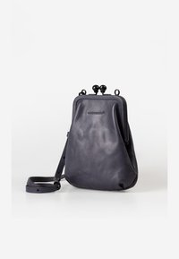 Borsa a tracolla in pelle blu navy con una texture morbida, forma arrotondata e chiusura a chiave. Dotata di un manico rimovibile per una maggiore versatilità.