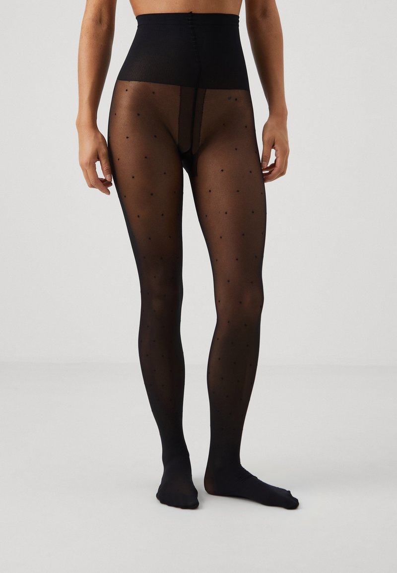 Svarta mönstrade strumpbyxor med hög midja, med små, jämnt fördelade prickar på ett genomskinligt material. Slät textur, åtsittande design.
