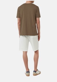 Braunshortsleeve T-Shirt, weiße strukturierte Shorts, hellfarbene Sneaker mit blauen Akzenten. Einfaches Design, lässige Passform.