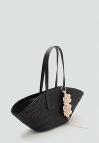 Borsa in paglia intrecciata nera con forma curvata, manici in pelle e un accento floreale rosa staccabile. Texture liscia con costruzione robusta.