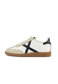 Sneakers with a white leather upper, beige suede accents, black leather heel, and a textured gum rubber sole. Features white laces and a cross pattern.