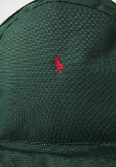 Mochila de tela verde con un pequeño logo de caballo bordado en rojo. Material texturizado con una forma estructurada y redondeada, y un detalle en la costura inferior.