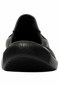 Zapato negro sin cordones que presenta un upper de cuero suave y una suela de goma estriada. En el interior tiene un forro acolchado. Talla marcada como 38 en la suela.