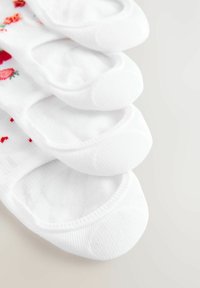 Vita bomullssockor med blommönster; varje strumpa har en låg skärning, elastiska öppningar och en mjuk textur. Fyra par visas.
