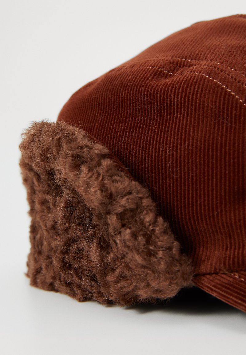 Brown corduroy cap with plush brown fleece ear flaps, featuring a slightly curved shape and subtle stitching details.