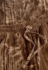 Braunes Wickelkleid aus einem strukturierten, samtigen Stoff mit einem subtilen Muster. Elastischer Taillenbund mit einer Bindung vorne.