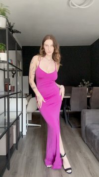 Vestido longo e justo em tecido rosa brilhante com um decote V profundo e alças finas. Apresenta uma fenda lateral e é combinado com sandálias de salto pretas.