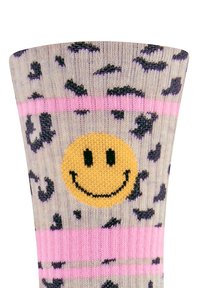 Strumpf aus Wolle mit beigem Grund, schwarzem Leopardenmuster und Grafik eines gelben Smileys. Mit rosa Streifen nahe dem oberen Rand als Akzent.