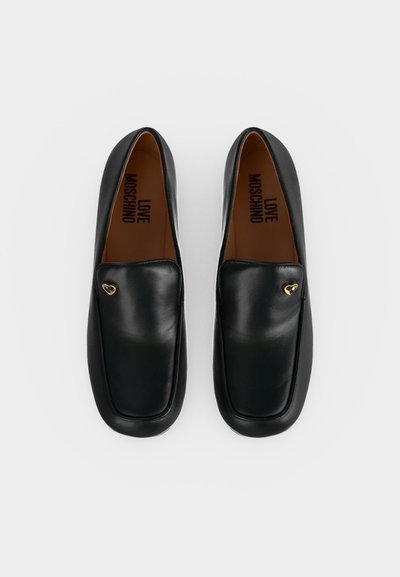 Paire de mocassins en cuir noir à bouts carrés avec petits accents dorés en forme de cœur, présentant le logo Love Moschino à l'intérieur.