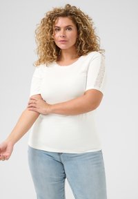 Biała, prążkowana koszulka z krótkim rękawem z koronkowymi wykończeniami na ramionach. Miękka tekstura, dopasowany krój, okrągły dekolt oraz lekki stretch.