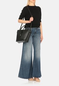 Borsa a tracolla in pelle nera con doppi manici, base piatta e tracolla regolabile; design strutturato, texture liscia, hardware minimale.