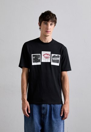 Sort bomuld t-shirt med tre trykte designs: en sikkerhedsnål, røde læber og "MOSCHINO" tekst, alle på hvide firkanter. Casual pasform.