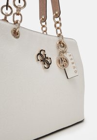 Hvid tote taske med prægede logo mønster, hardware i guld-tone og kæde-lænker stropper. Har hængende mærkater og detaljer.