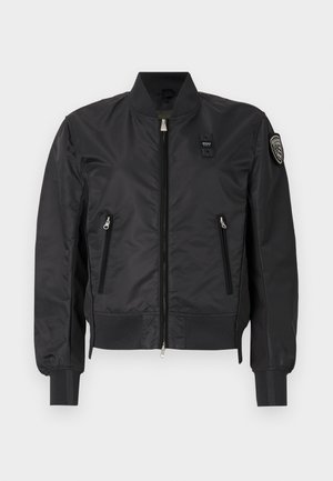 Giubbotto bomber nero realizzato in tessuto liscio e lucido. Presenta una chiusura frontale con zip, orlo e polsini a costine, e due tasche laterali con zip. Accompagnato da un Toppa sulla manica.