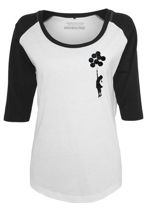 Valge ja must 3/4 varrukatega särk, millel on must siluett graafika kujutis figuurist, kes hoiab õhupalle, pehmest puuvillast tekstuurist.