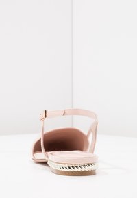 Rosa sandaler i blush med en tunn rem kring vristen, glänsande yta och en flätad silverdetalj på sulan. Öppen tå-design för andningsförmåga.