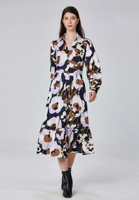 Robe midi à motif floral avec un devant boutonné, des manches longues et un ourlet à volants superposés dans des couleurs noir, blanc, marron et lilas.