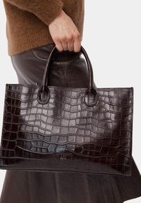 Borsa a mano in pelle con stampa coccodrillo di colore marrone scuro, dotata di due manici rotondi e dalla forma rettangolare, che mostra una texture lucida e dettagli di cucitura sottili.