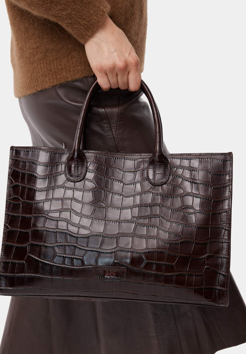 Borsa a mano in pelle con stampa coccodrillo di colore marrone scuro, dotata di due manici rotondi e dalla forma rettangolare, che mostra una texture lucida e dettagli di cucitura sottili.