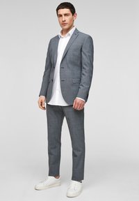 Grijs geruit pak met een knoopjasje en broek met flat front, gecombineerd met een witte overhemden en witte sneakers. Soepele, op maat gemaakte pasvorm.