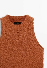 Pull sans manches en tricot orange brûlé. Présente un col rond côtelé et des côtés ouverts. Texture douce avec un motif de tricot épais.