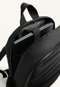 Fekete hátizsák, párnázott rekesszel, amely laptop tárolására alkalmas. Sima anyagból készült, strukturált kialakítással, cipzáras záródással és állítható pántokkal.