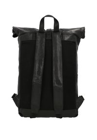 Sac à dos noir à rabat, fabriqué en cuir et tissu, doté de deux bretelles réglables et d'une poignée supérieure pour un transport polyvalent.