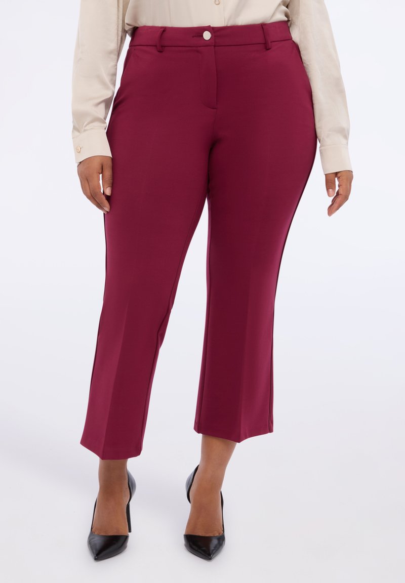 Pantalons bourgogne au toucher lisse, coupe slim, design élégant et taille standard, associés à des escarpins noirs à bout pointu.