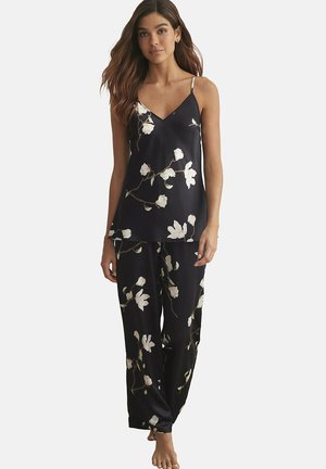 Ensemble de pyjama en satin noir léger avec des imprimés floraux blancs. Caraco à fines bretelles, associé à un pantalon ample.