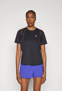 Μαύρο αθλητικό t-shirt με διακριτικές διαφάνειες στους ώμους, με στρογγυλή λαιμόκοψη και λογότυπο. Συνδυάζεται με μωβ σορτς.