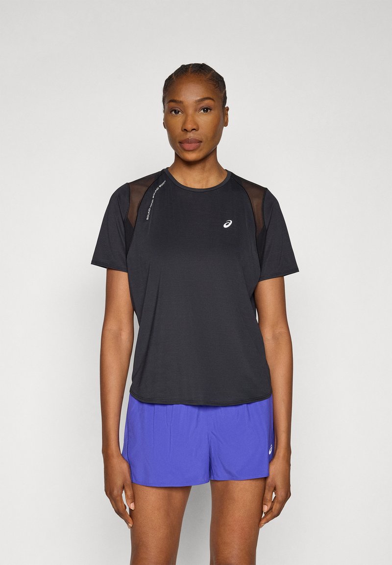 Μαύρο αθλητικό t-shirt με διακριτικές διαφάνειες στους ώμους, με στρογγυλή λαιμόκοψη και λογότυπο. Συνδυάζεται με μωβ σορτς.