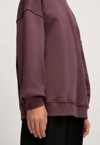 Bordeauxrotes Sweatshirt mit lockerer Passform, gerippten Bündchen und Saum. Weicher Stoff mit glatter Oberfläche, ausgestattet mit überschnittenen Schulternähten.