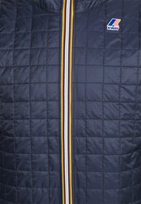 Marineblauw gequilt vest met hoge kraag en een vooraanstaande rits. Voorzien van een gestreepte rits in wit, geel en oranje, met een K-Way-logo.