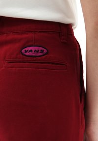Pantaloni di cotone rossi con tasca posteriore dotata di un patch con il logo Vans nero e viola, tessuti misti e design a vita aderente.