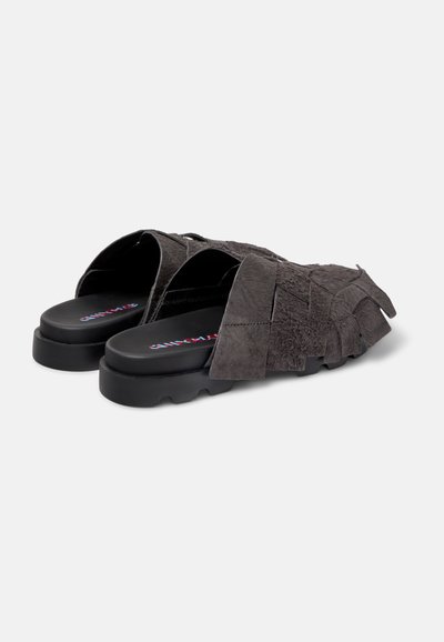 Suede gray slip-on shoes with an open back, featuring a layered fringe design and black rubber soles. Notable branding on the insole.