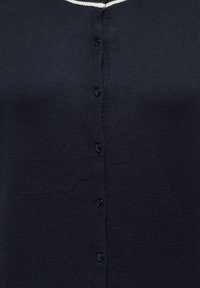 Cardigan noir boutonné avec un détail de bordure blanche au niveau de l'encolure, présenté de face.
