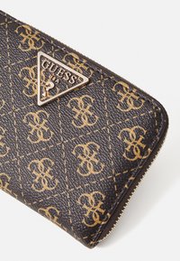 Portafoglio nero con texture, logo dorato e design decorato, con chiusura a zip e un accentuato elemento hardware triangolare.