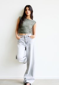 Groen textuur crop top gecombineerd met hoge taille, losvallende lichtgrijze spijkerbroek. De jeans hebben een klassieke vijf-pocket ontwerp.