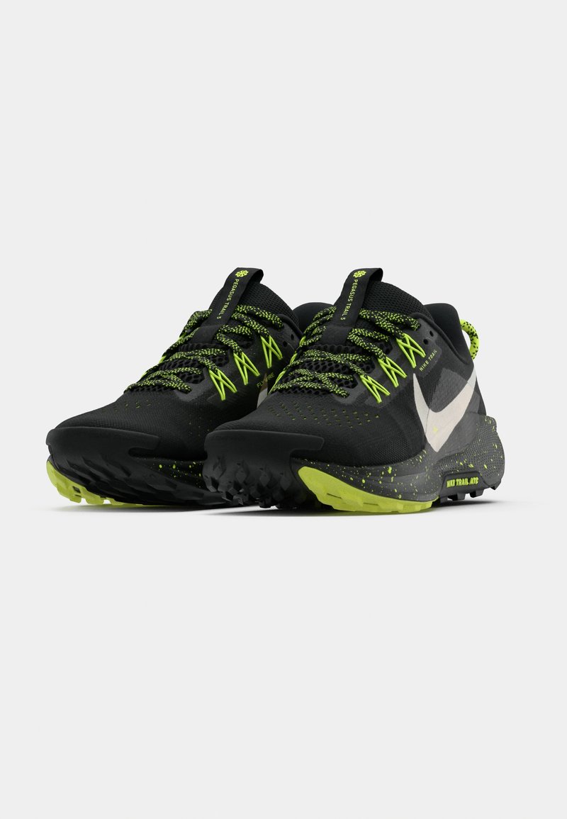 Zapatillas deportivas negras con detalles en verde neón, parte superior de tela texturizada, suela robusta de goma con patrón de agarre para senderos y detalles reflectantes.