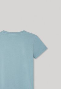 Camiseta de manga corta en azul claro, fabricada en algodón suave. Presenta un cuello redondo y una textura lisa, con un diseño simple y sin patrones visibles.